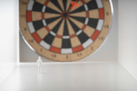 Businessman figurine standing in front of dartboard.の写真素材