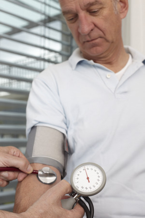 Mature man at medical examination, measuring blood pressureの写真素材