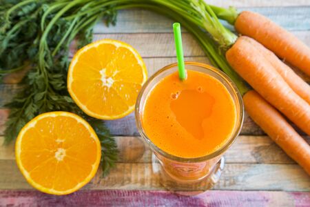 Orange carrot smoothie in glass on woodの写真素材