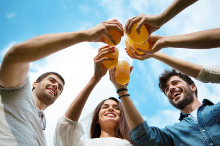 Group of friends toasting with beer in plastic glassesの写真素材