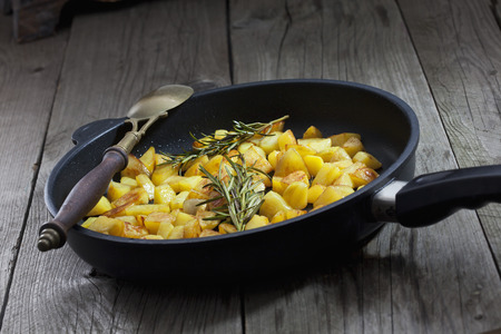 Fried potatoes and thyme in pan, old spoonの写真素材
