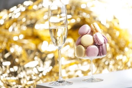 Macarons in glass with a glass of champain, golden backgroundの写真素材