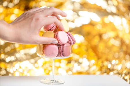 Hand taking a macaron, golden backgroundの写真素材