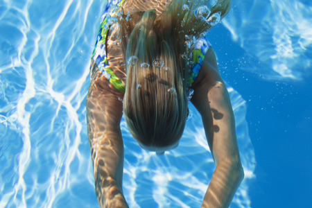 Swimming pool, woman swimming under waterの写真素材