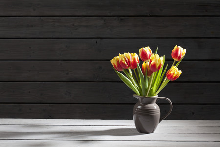 Tulips in vase, wooden backgroundの写真素材