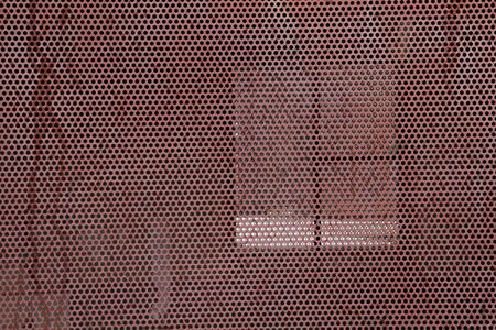 Perforated iron board in front of windowの写真素材
