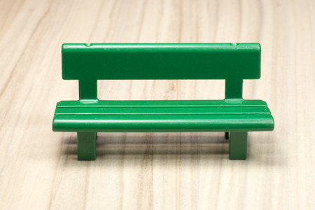 Green miniature bench on woodの写真素材