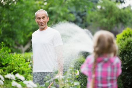 Father and daughter watering plants in gardenの写真素材