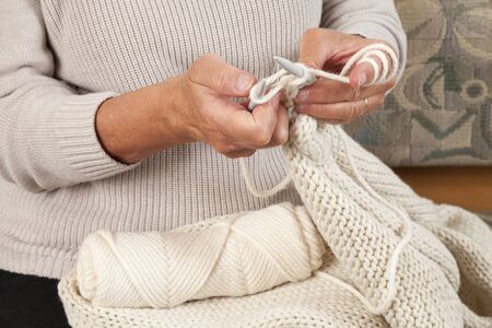 Hands knitting white scarf, pullover