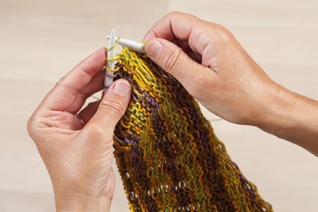 Hands knitting colorful scarf