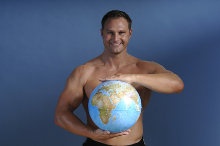 Man holding globe, smiling, portraitの写真素材