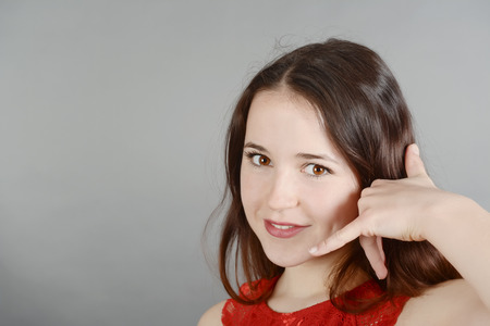 Young woman making hand gestures, calling, on the phoneの写真素材