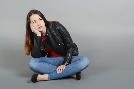 Thoughtful young woman in sitting on ground