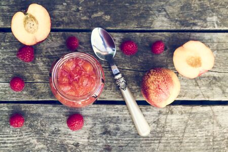 Raspberry nectarine jam in glass on woodの写真素材