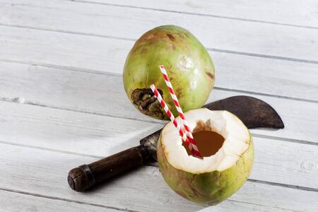 Coconut with drinking straws, cleaver on woodの写真素材