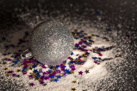 Silver bauble on colorful glitter starsの写真素材