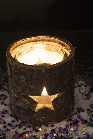 Burning candle in tea light holder with starsの写真素材