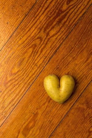 Heart potato on woodの写真素材