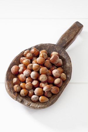 Hazelnuts on wooden spoon on white backgroundの写真素材