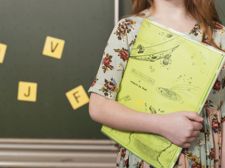 Girl (4-7) holding exercise-book, mid-section