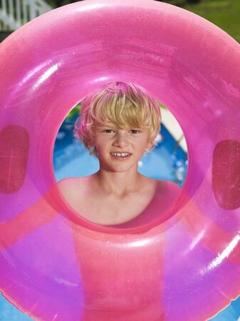 Boy holding pink rubber ring, portraitの写真素材