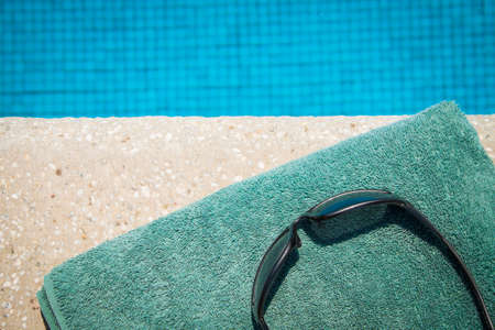 Sunglasses and towel at the edge of swimming poolの写真素材