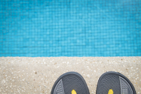 Flipflop sandals at edge of swimming poolの写真素材