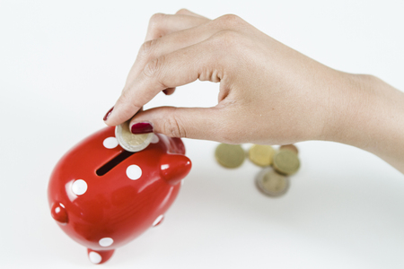 Woman saving money with red piggy bankの写真素材