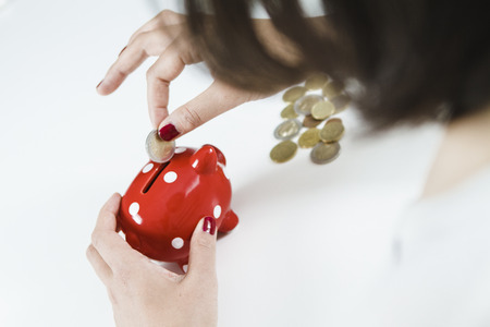 Woman saving money with red piggy bankの写真素材