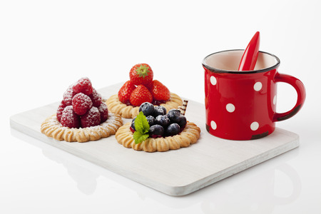 Tartlets, raspberry, strawberry and blueberries with coffee cupの写真素材
