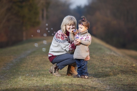Grandmother and granddaughter blowing bubblesの写真素材