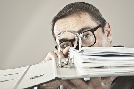 Close up of mature businessman looking through ring binderの写真素材
