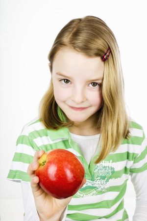 Girl holding apple against white background,smiling,portraitの写真素材