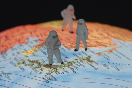 Close up of miniature figurines of astronomers on globe against black 