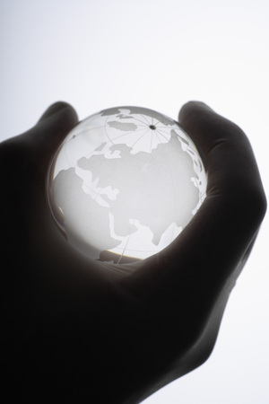 Human hand with medical gloves gripping glass globe against white ,close upの写真素材
