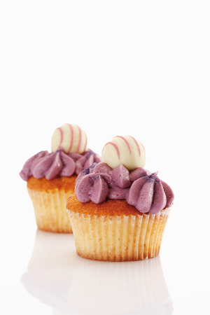 Close up of buttercream black currant cupcake with chocolate truffle against white の写真素材