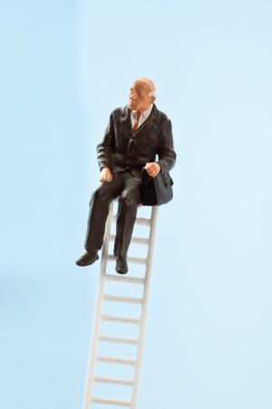 Businessman figurine sitting on ladderの写真素材