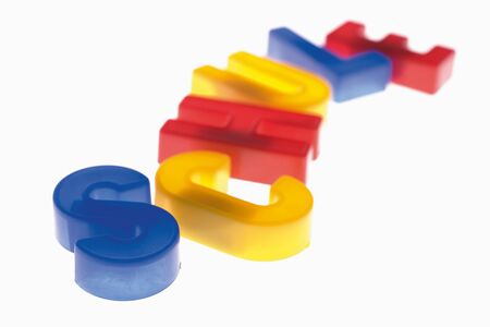 Close up of colourful plastic letters reading school against white 