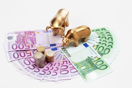 Golden bear and bull figurines with euro coins on fanned euro notesの写真素材