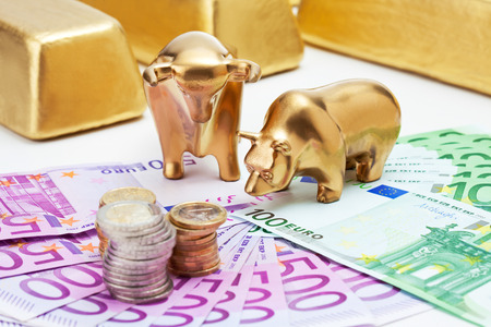 Golden bear, bull figurines with euro coins  gold bars on fanned euro notesの写真素材