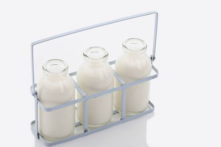 Close up of milk bottles in rack on white backgroundの写真素材