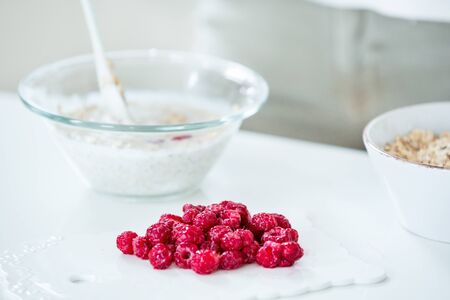 Red raspberries, muesli bowl in the backgroundの写真素材