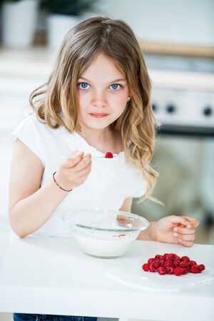 Young girl eating muesli with raspberriesの写真素材