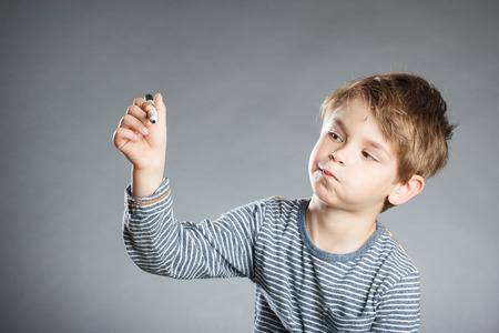 Portrait of boy with pen, emotion, thoughtful, grey backgroundの写真素材