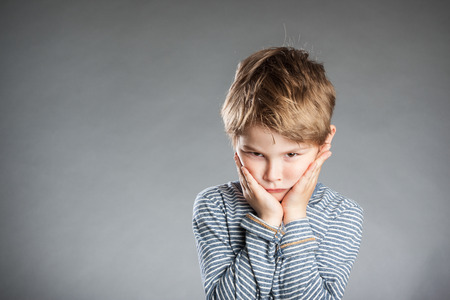 Portrait of boy, emotion, pouting, grey background