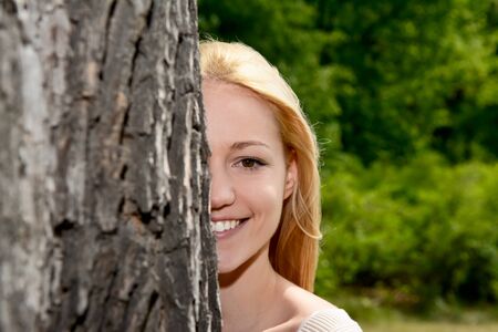 Happy young woman on a tree in parkの写真素材
