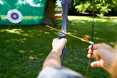 Germany,Mecklenburg-Western Pomerania,boy aiming target with bow and arrow