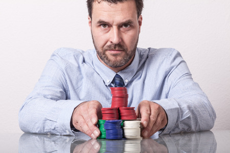 Mature man with poker chips on glass table, placing his betの写真素材
