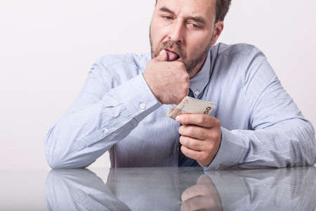 Mature man counting euro notes at glass desk