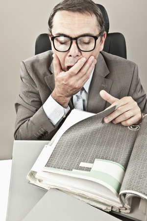 Close up of mature businessman yawning in officeの写真素材